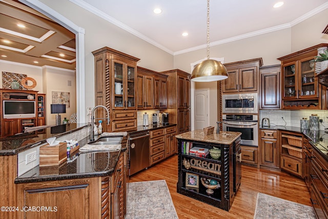 kitchen featuring hanging light fixtures, stainless steel appliances, backsplash, dark stone counters, and a kitchen island with sink