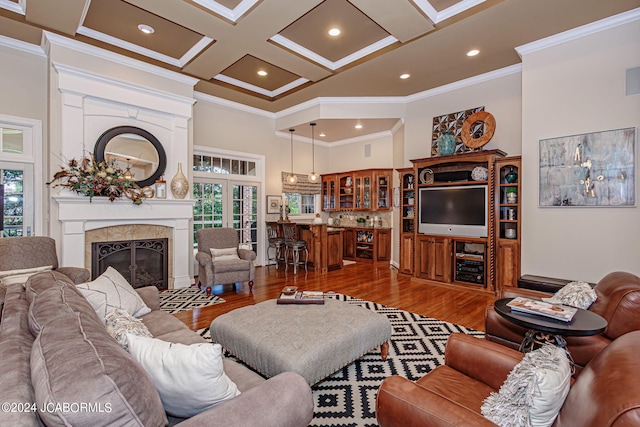 living room featuring crown molding, a fireplace, coffered ceiling, and hardwood / wood-style flooring