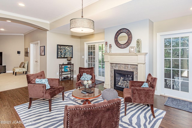 living area featuring a fireplace, arched walkways, ornamental molding, recessed lighting, and wood finished floors
