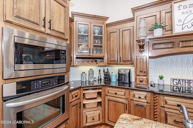 kitchen featuring stainless steel appliances, tasteful backsplash, and dark stone counters