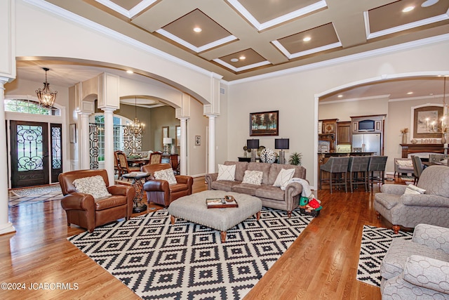 living room featuring wood-type flooring, ornate columns, coffered ceiling, and crown molding