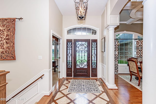 foyer entrance featuring decorative columns, an inviting chandelier, and light hardwood / wood-style floors