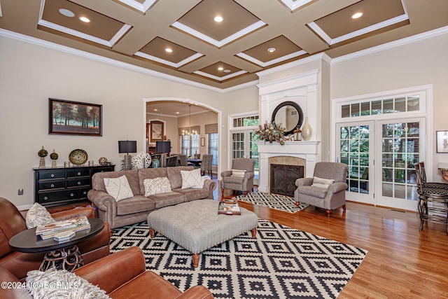 living room featuring a fireplace, a towering ceiling, coffered ceiling, and ornamental molding