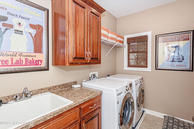laundry room with baseboards, light tile patterned floors, cabinet space, washer and dryer, and a sink