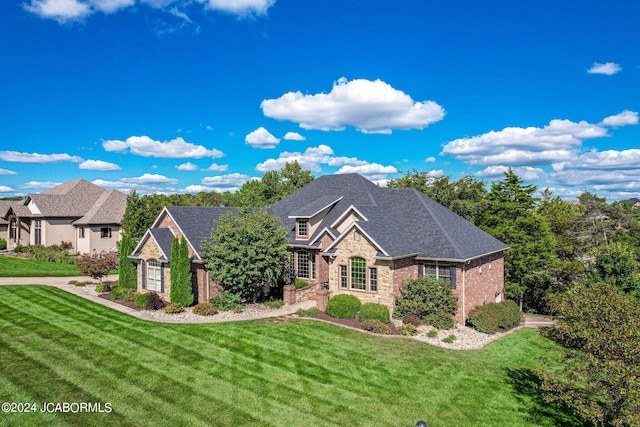 view of front of home with roof with shingles, a front lawn, and brick siding