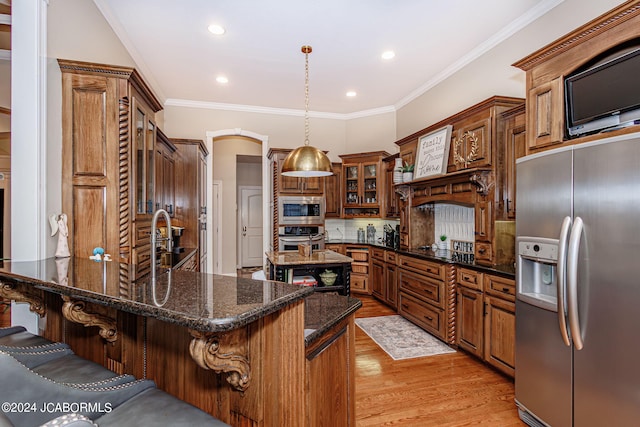 kitchen featuring dark stone counters, a kitchen breakfast bar, appliances with stainless steel finishes, decorative light fixtures, and a kitchen island