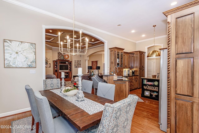 dining space with a notable chandelier, light hardwood / wood-style floors, ornamental molding, and sink