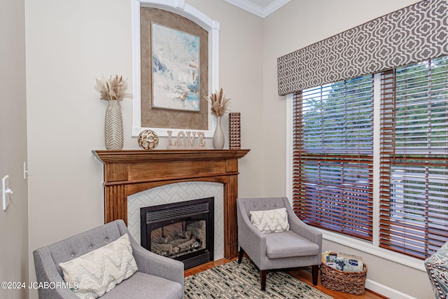 living area featuring a tile fireplace, hardwood / wood-style flooring, and crown molding