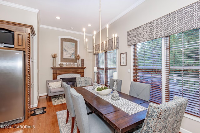 dining area with light hardwood / wood-style floors, ornamental molding, and a notable chandelier