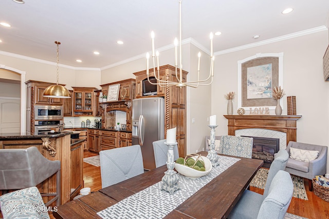 dining area featuring crown molding, light wood-type flooring, and a fireplace