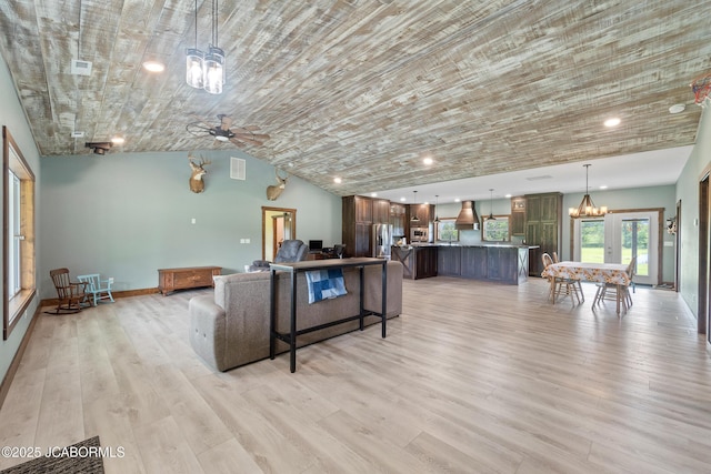 8596 County Rd 146, Williamsburg, MO 63388 - living area with visible vents, lofted ceiling, baseboards, light wood-type flooring, and ceiling fan with notable chandelier
