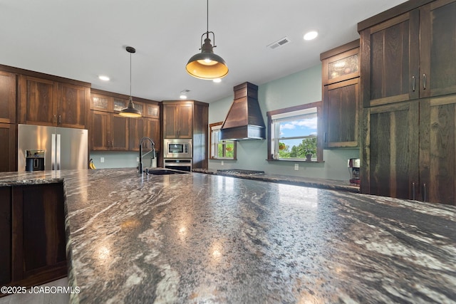 8596 County Rd 146, Williamsburg, MO 63388 - kitchen featuring a sink, premium range hood, stainless steel appliances, decorative light fixtures, and visible vents
