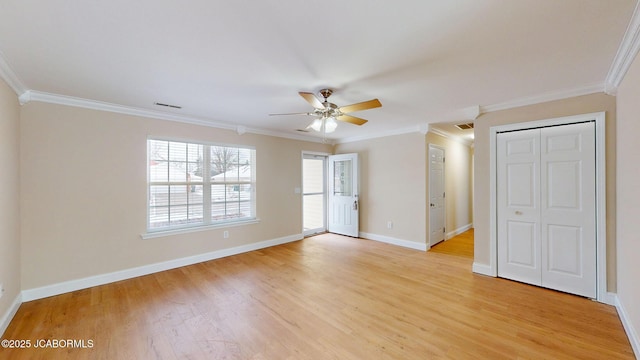 empty room with crown molding, light wood finished floors, visible vents, a ceiling fan, and baseboards