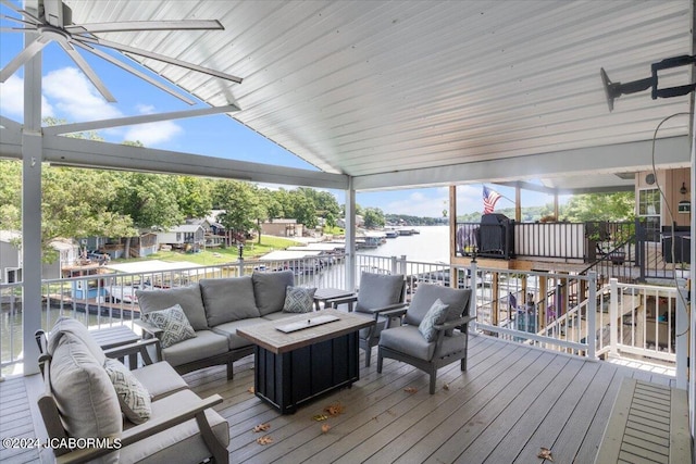 wooden terrace with an outdoor living space with a fire pit and a water view