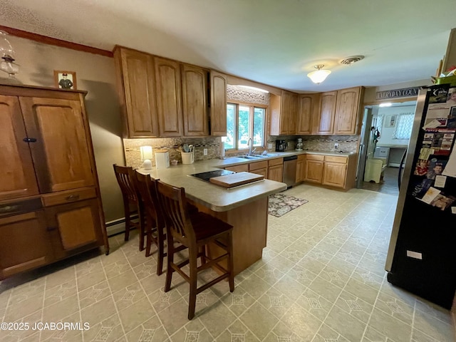 501 W Morgan St, Tipton, MO 65081 - kitchen with freestanding refrigerator, dishwasher, a peninsula, tasteful backsplash, and a kitchen breakfast bar