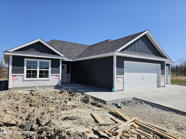 view of front of home with board and batten siding, concrete driveway, a garage, and roof with shingles