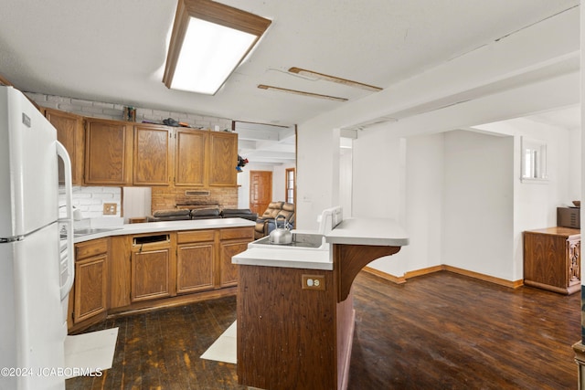 kitchen featuring a center island, dark wood-type flooring, white refrigerator, backsplash, and a kitchen bar