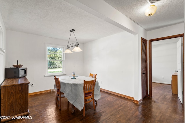 dining area featuring dark hardwood / wood-style flooring and a textured ceiling