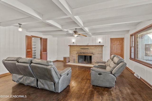 living room featuring coffered ceiling, a stone fireplace, dark hardwood / wood-style floors, ceiling fan, and beam ceiling