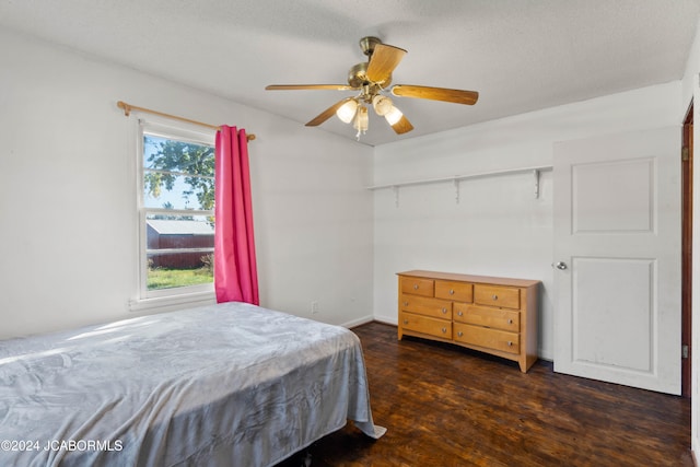 bedroom featuring ceiling fan, dark hardwood / wood-style flooring, and a textured ceiling