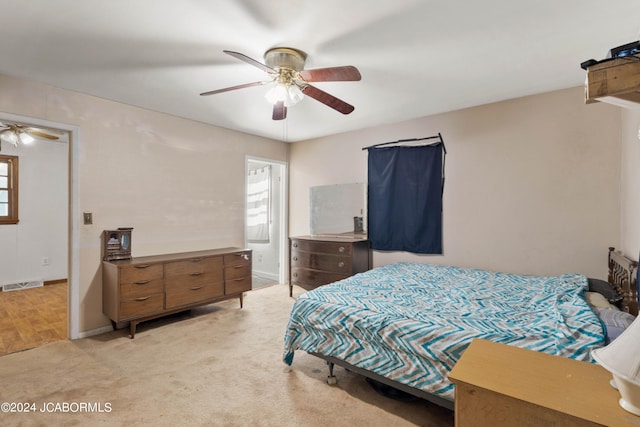 bedroom with connected bathroom, light colored carpet, and ceiling fan