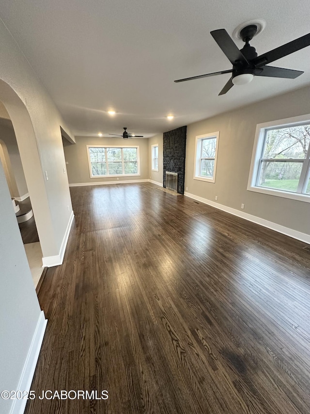 1434 Sunset Lake Rd, Jefferson City, MO 65109 - unfurnished living room with arched walkways, dark wood-style floors, ceiling fan, and plenty of natural light