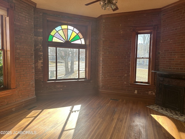 unfurnished living room featuring brick wall, dark hardwood / wood-style floors, a textured ceiling, and a fireplace