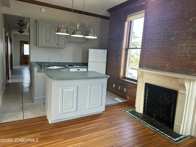 kitchen with sink, hanging light fixtures, gray cabinets, white fridge, and hardwood / wood-style floors