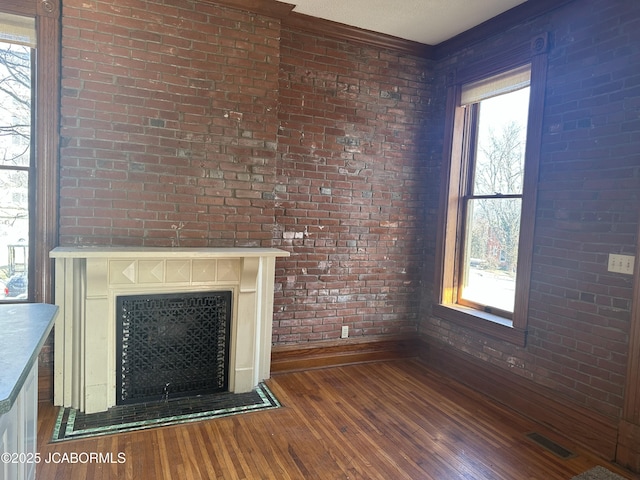 unfurnished living room with brick wall and dark hardwood / wood-style flooring