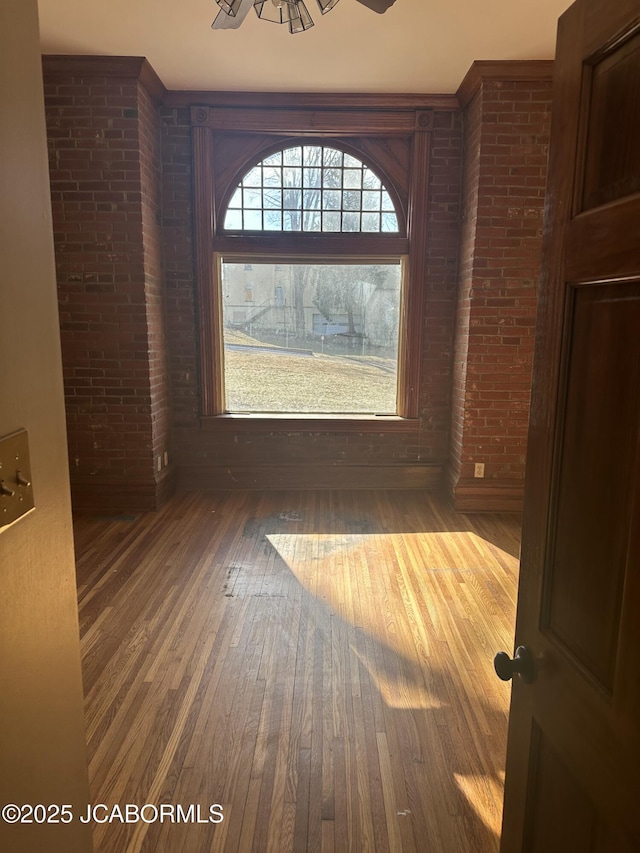 spare room with brick wall and dark hardwood / wood-style flooring