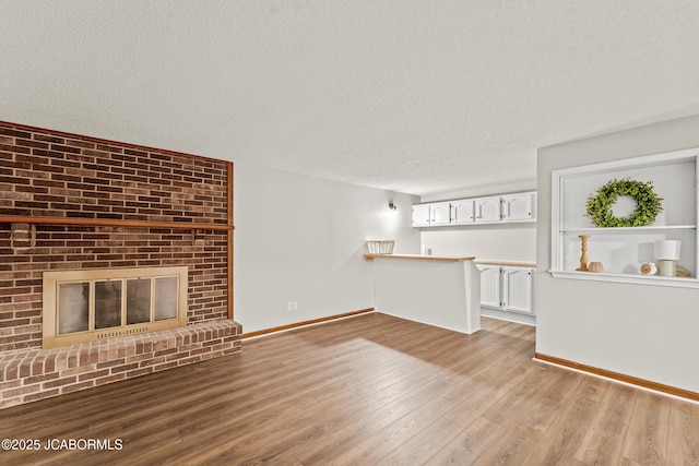 4300 W E Ridge Rd, Columbia, MO 65202 - unfurnished living room with a textured ceiling, light wood-style floors, baseboards, and a fireplace