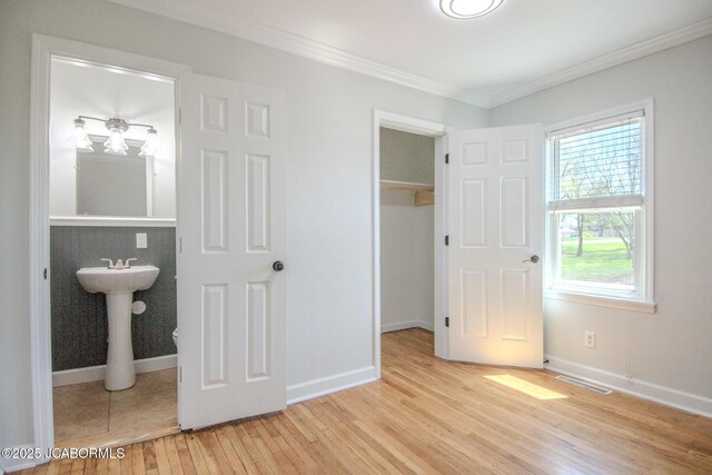12271 County Road 4037, Holts Summit, MO 65043 - unfurnished bedroom featuring a closet, light wood-style flooring, a walk in closet, ornamental molding, and baseboards