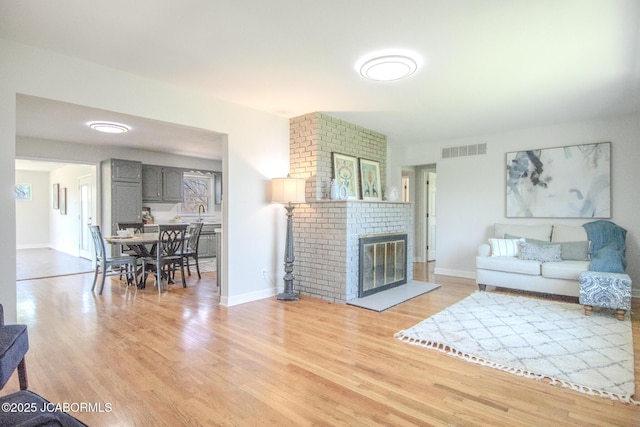 12271 County Road 4037, Holts Summit, MO 65043 - living area with light wood-type flooring, baseboards, and a brick fireplace