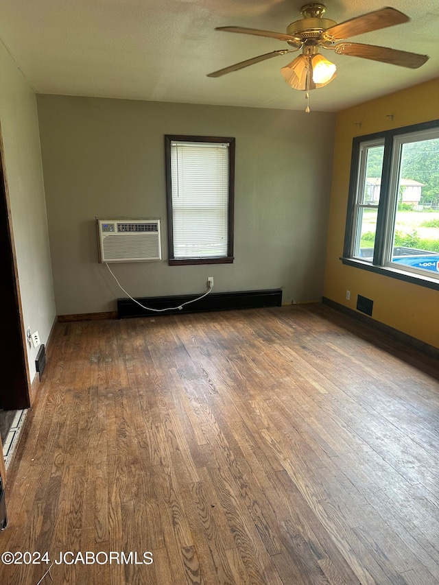 empty room featuring hardwood / wood-style flooring, ceiling fan, and a wall unit AC