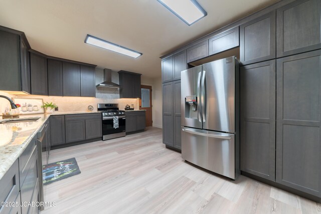 232 Pheasant Ln, Holts Summit, MO 65043 - kitchen with stainless steel appliances, wall chimney exhaust hood, light wood finished floors, tasteful backsplash, and light stone countertops