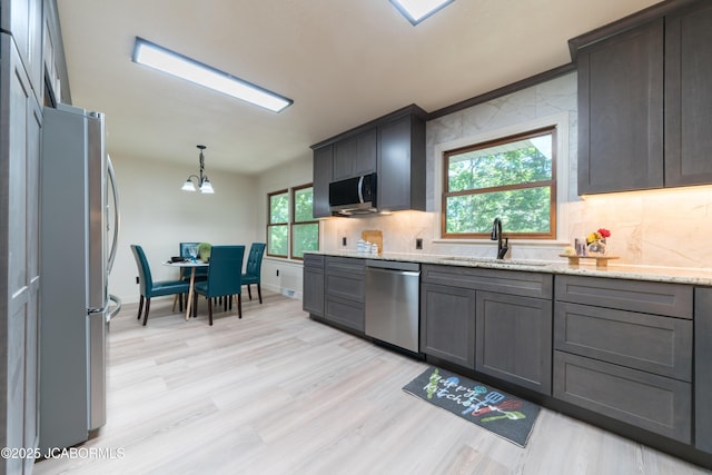 232 Pheasant Ln, Holts Summit, MO 65043 - kitchen featuring stainless steel appliances, tasteful backsplash, light stone counters, light wood finished floors, and decorative light fixtures