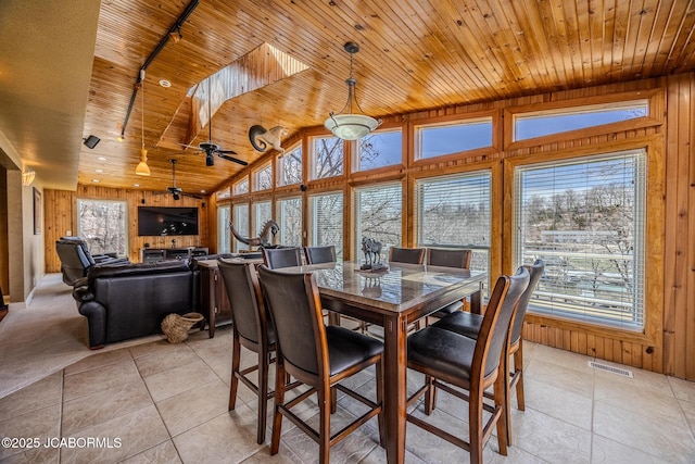 dining area with wooden walls, light tile patterned floors, wooden ceiling, lofted ceiling, and visible vents