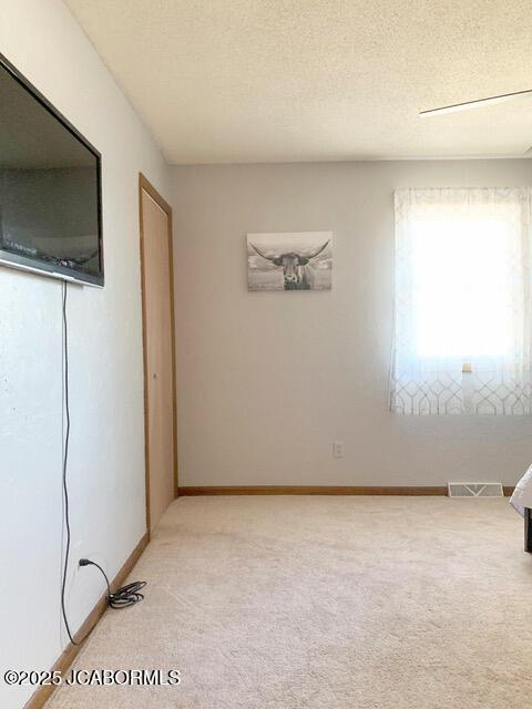 carpeted empty room featuring a textured ceiling