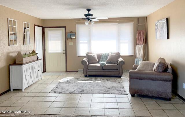 living room with ceiling fan, light tile patterned floors, and a textured ceiling