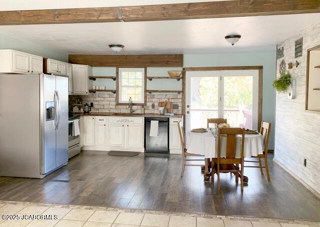 kitchen with white cabinetry, light hardwood / wood-style floors, stainless steel appliances, beam ceiling, and sink