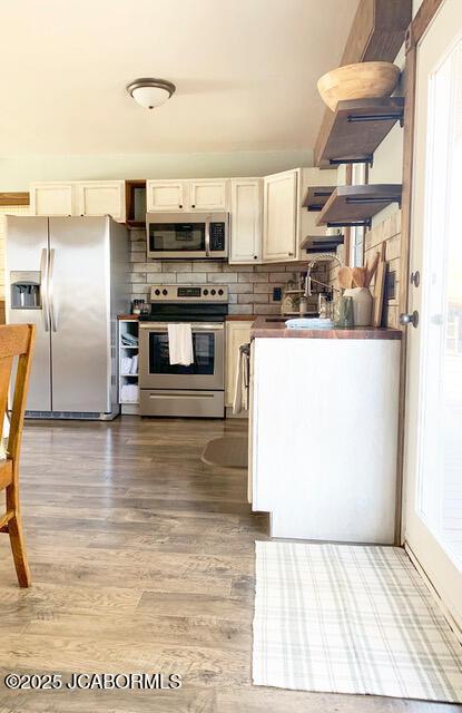 kitchen featuring wood-type flooring, decorative backsplash, sink, stainless steel appliances, and cream cabinets