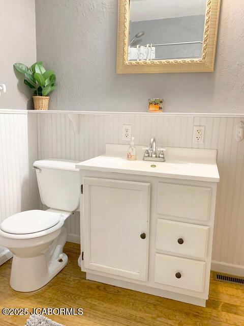 bathroom with wood-type flooring, toilet, and vanity