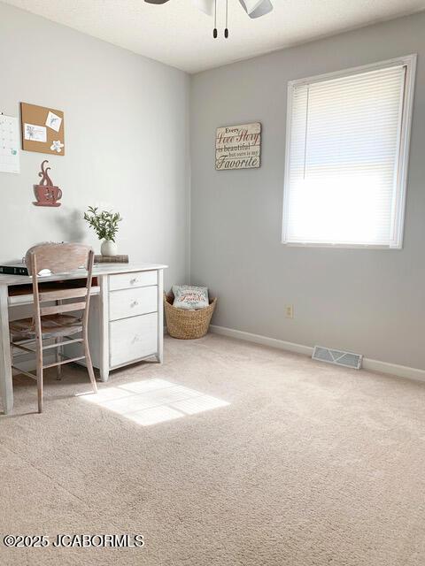 carpeted office space with ceiling fan