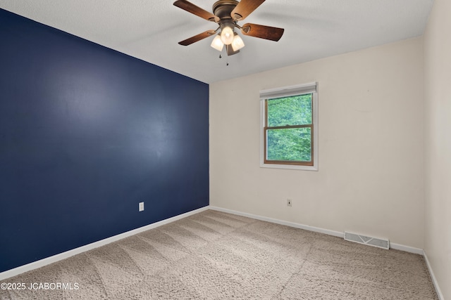 carpeted empty room with baseboards, a ceiling fan, and visible vents