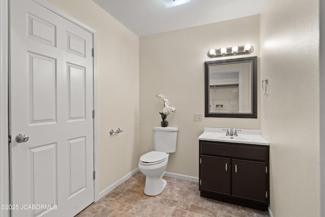 bathroom featuring baseboards, a textured ceiling, toilet, and vanity