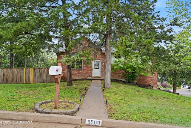 view of front of property with brick siding, fence, and a front yard