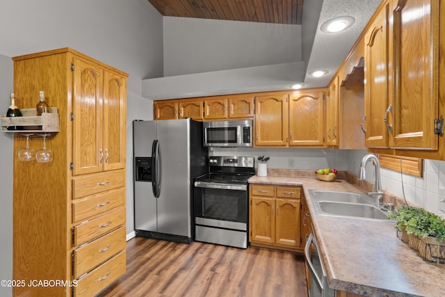 kitchen with decorative backsplash, wood finished floors, light countertops, a sink, and stainless steel appliances