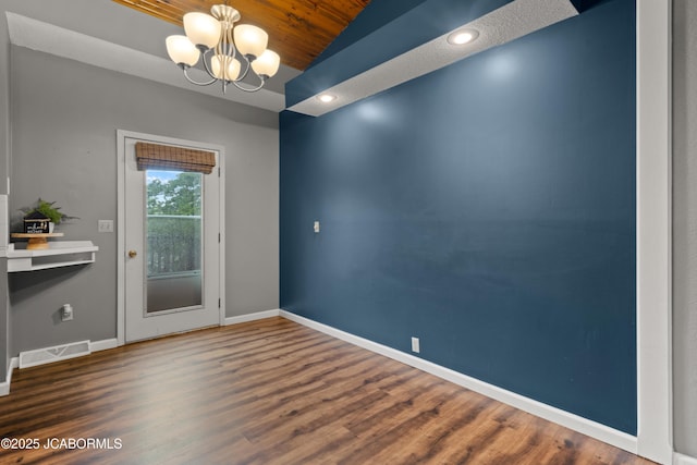 unfurnished dining area with visible vents, wood finished floors, baseboards, wood ceiling, and a notable chandelier