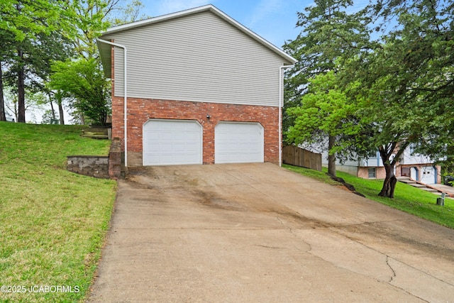 view of property exterior featuring an attached garage, a yard, brick siding, and concrete driveway
