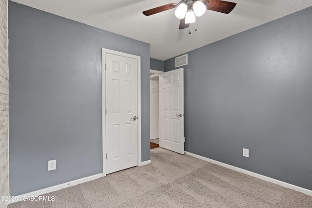 unfurnished bedroom featuring carpet floors, baseboards, visible vents, and ceiling fan
